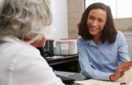 a smiling woman speaks with a senior
