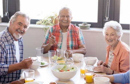 residents seated at a table with meals in front of them smiling